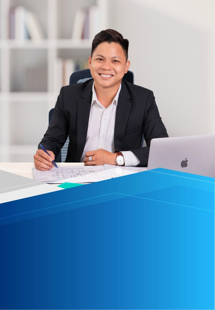CEO Nguyễn Văn Lộc ngồi làm việc tại bàn với bản vẽ kỹ thuật và laptop